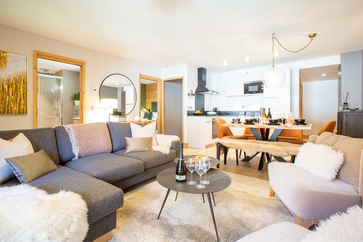A living room with a couch and a table with a bottle of wine on it