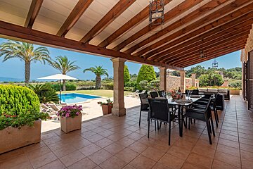 A patio with a table and chairs and a pool in the background
