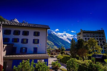 A white building with blue shutters and a mountain in the background