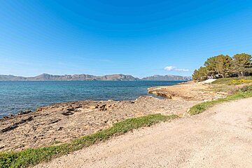 A dirt road leads to the ocean with mountains in the background