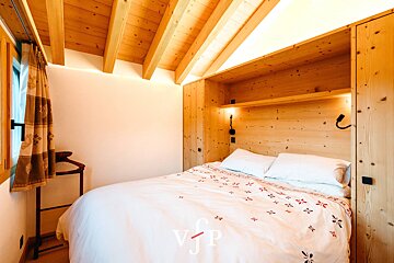 A bedroom with a wooden ceiling and a bed with a white comforter