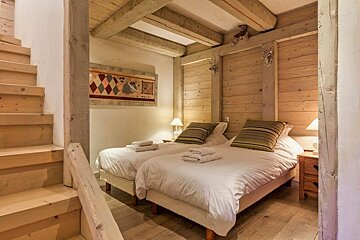 A bedroom with two beds and stairs leading up to it