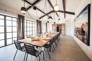 A dining room with a long wooden table and black chairs