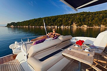 A woman in a bikini sits on the back of a boat