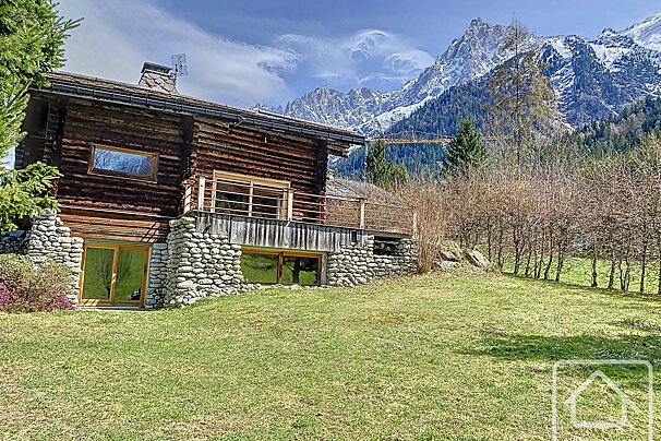 A log cabin with mountains in the background is for sale