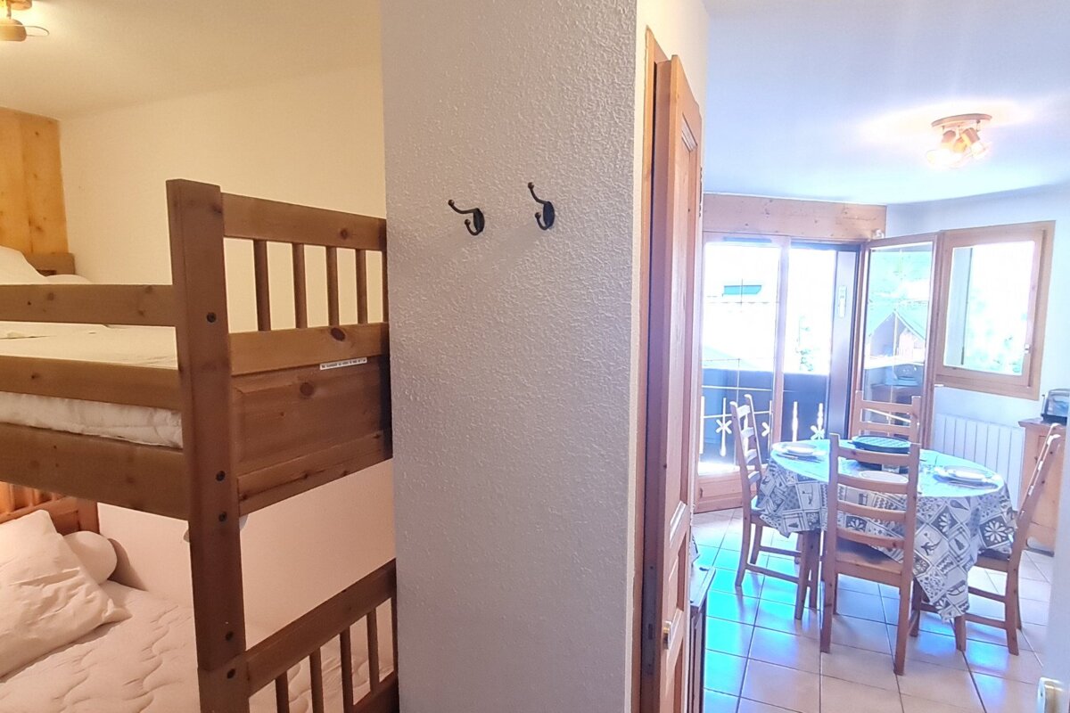 A bunk bed in a room next to a table and chairs