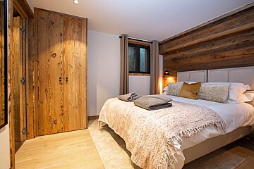 A bedroom with a bed and a wooden wall