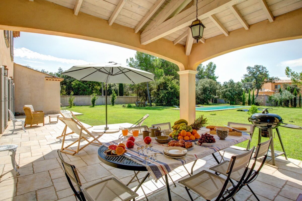 A table with fruit on it sits under an umbrella on a patio