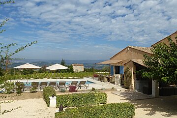 A house with a pool and umbrellas in front of it