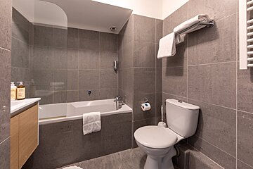 A bathroom with a toilet a bathtub and two bottles of lotion