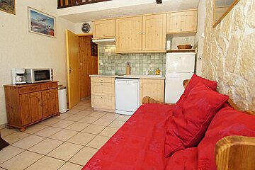 A kitchen with wooden cabinets and a red couch