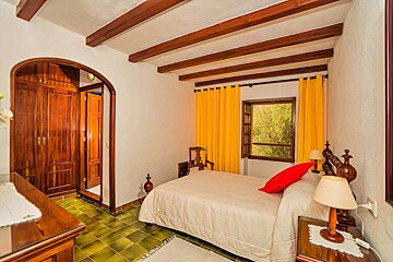 A bedroom with a bed and a window with yellow curtains