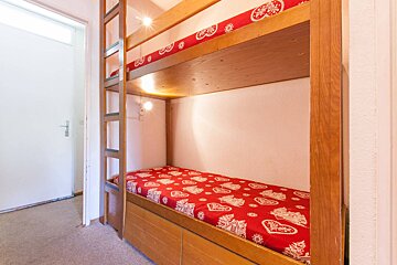 A bunk bed with a red blanket with hearts on it