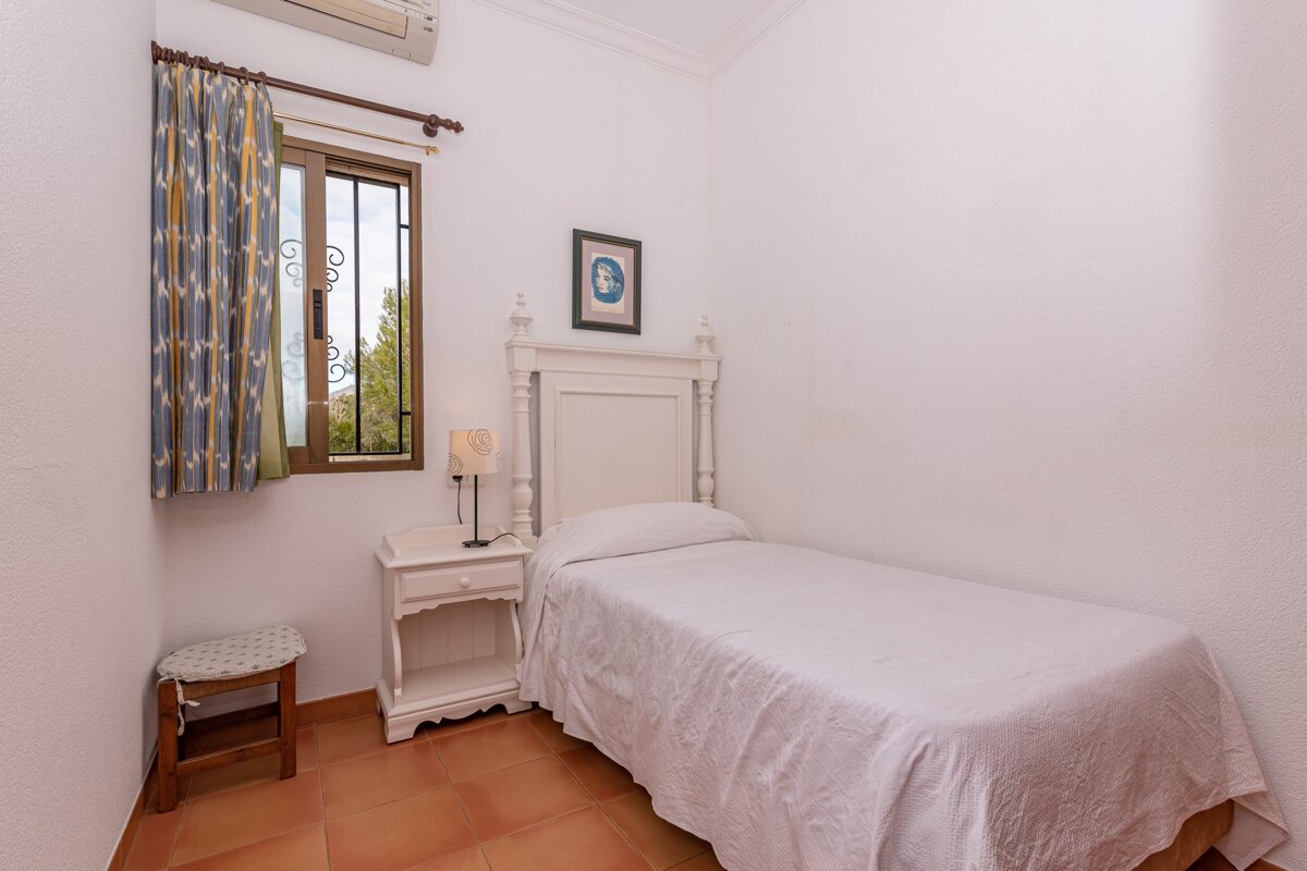 A bedroom with a single bed a nightstand and a window