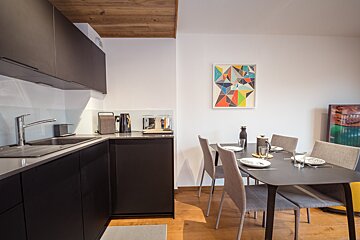 A kitchen with a table and chairs and a painting on the wall