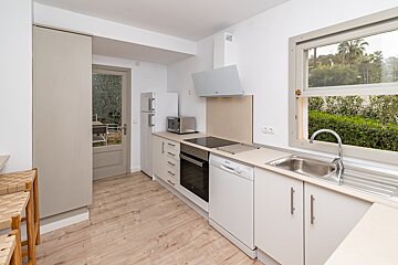 A kitchen with white cabinets and a stainless steel sink