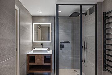 A bathroom with a walk in shower and a sink