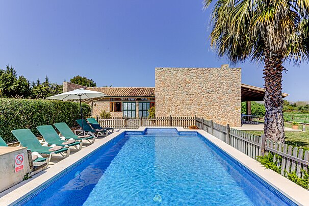 A large swimming pool is surrounded by chairs and umbrellas