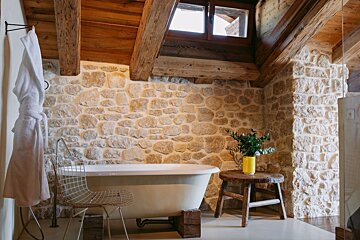 A bathtub in a bathroom with a stone wall