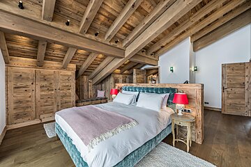 A bedroom with a wooden ceiling and a bed