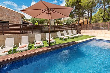 A row of lounge chairs next to a swimming pool under an umbrella