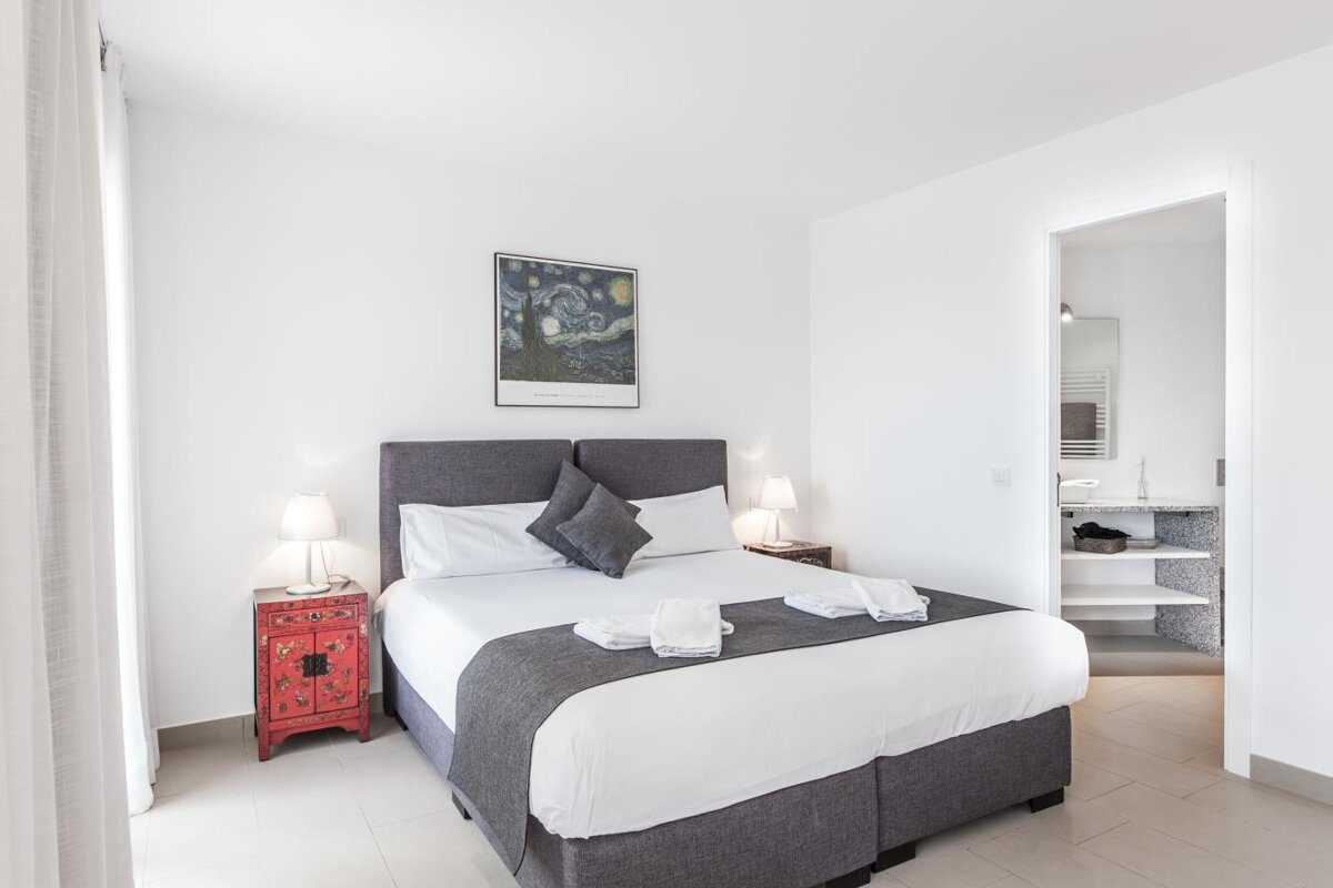 A bedroom with a painting on the wall above the bed