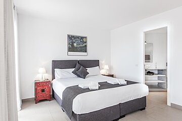 A bedroom with a painting on the wall above the bed