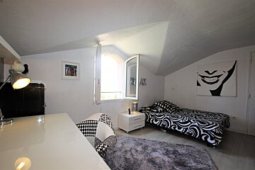 A bedroom with a painting of a smiling face on the wall