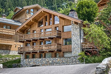 A large wooden house with a stone wall and balconies