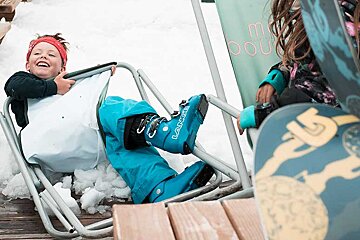 A child wearing blue la sportiva boots sits in a chair