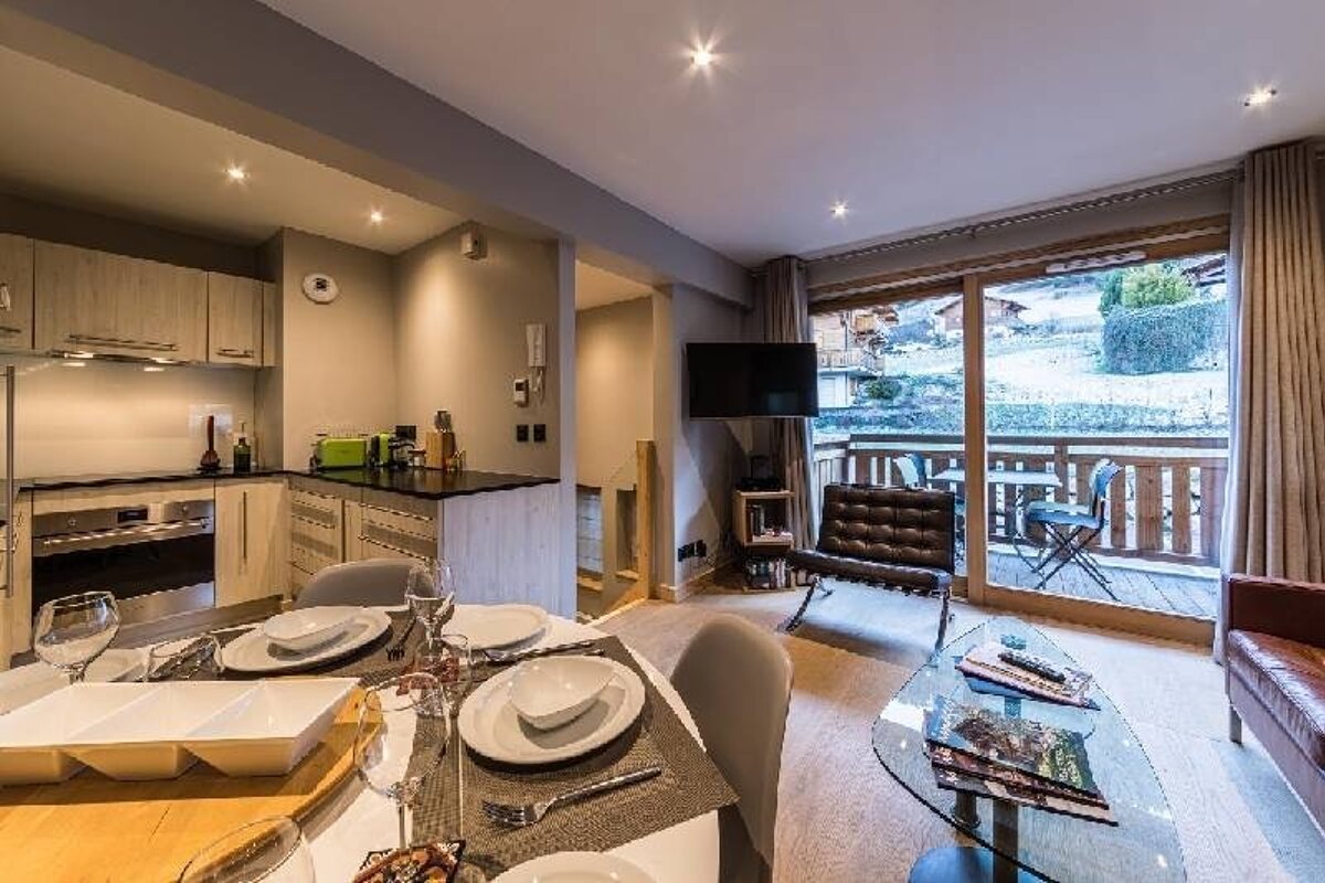 Modern apartment with a dining area, small kitchen, cozy living room, and large sliding doors opening to a balcony.