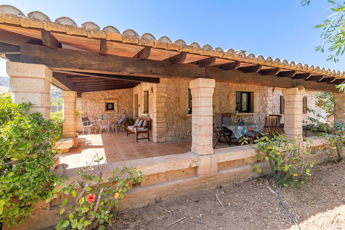 A patio with a table and chairs under a wooden roof