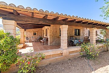 A patio with a table and chairs under a wooden roof