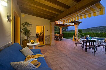 A patio with a yellow and white awning and a blue couch