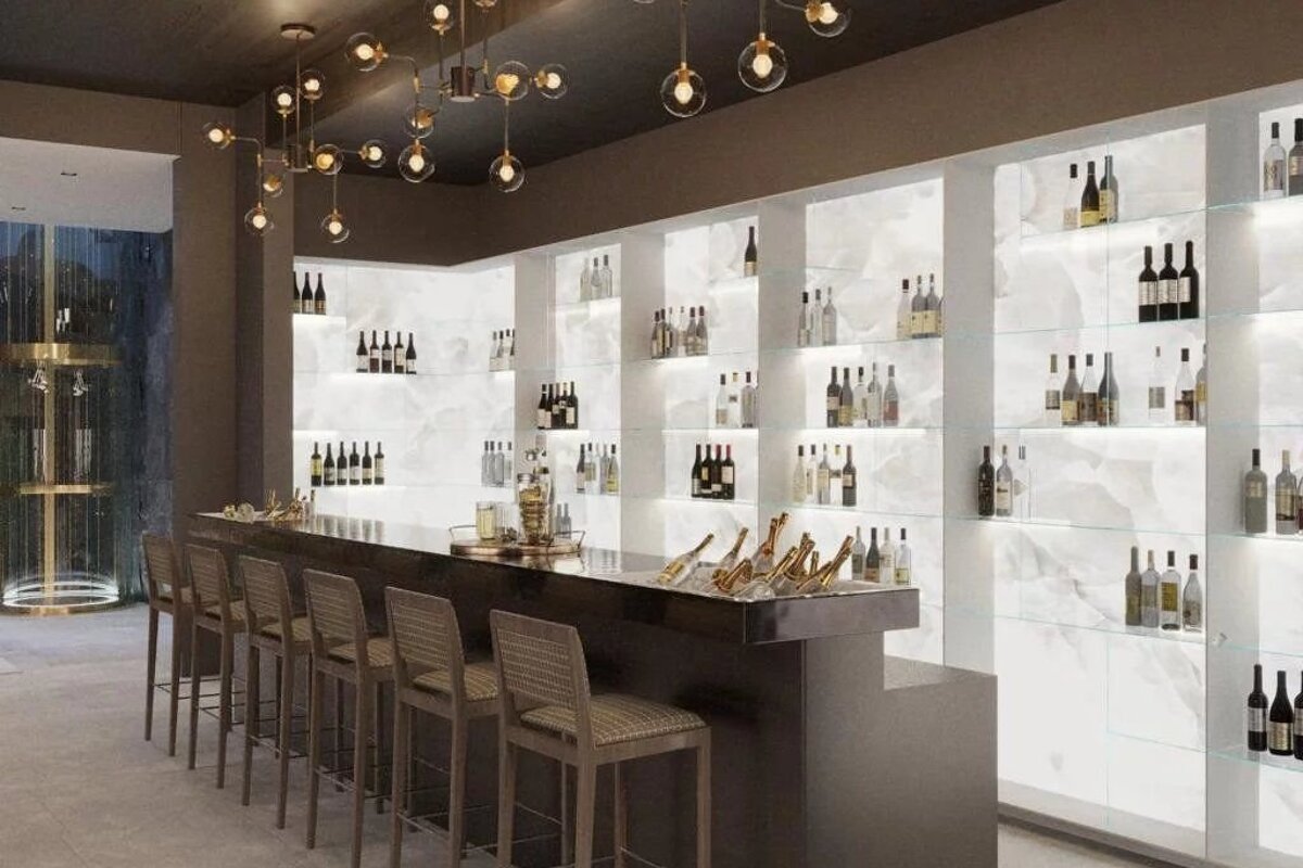 A chic, modern bar featuring sleek barstools, ambient pendant lighting, and glowing, backlit shelves stocked with wine.