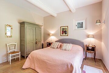 A bedroom with a pink bed and a painting on the wall