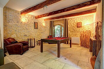 A pool table in a room with a stone wall