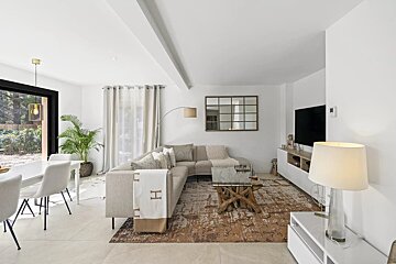 Bright, modern living room featuring a beige sectional sofa, a unique driftwood coffee table, patterned rug, and adjacent dining area.