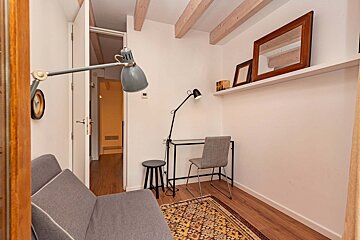 A room with a couch a desk and a lamp