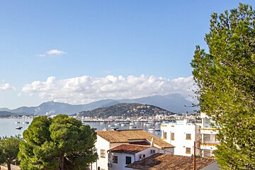 A view of a city with boats in the water and mountains in the background