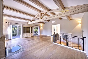 An empty living room with wooden beams and a staircase