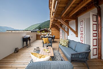 A balcony with a couch and a table with a bottle of wine on it