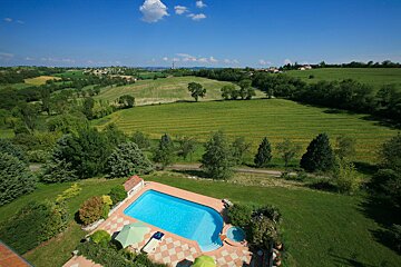 An aerial view of a swimming pool surrounded by lush green fields