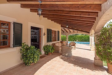 A house with a covered porch and a pool in the background