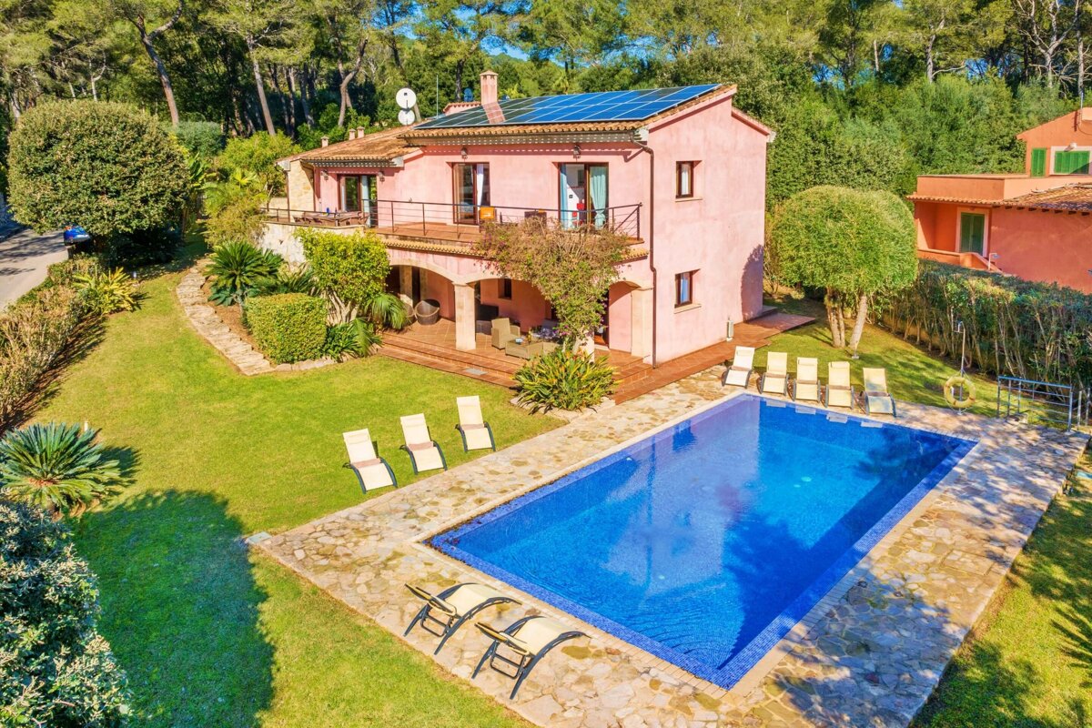 A pink house with a large swimming pool in front of it