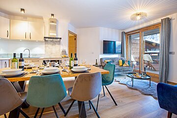 A living room with a table and chairs and a bottle of wine that says ' a ' on it