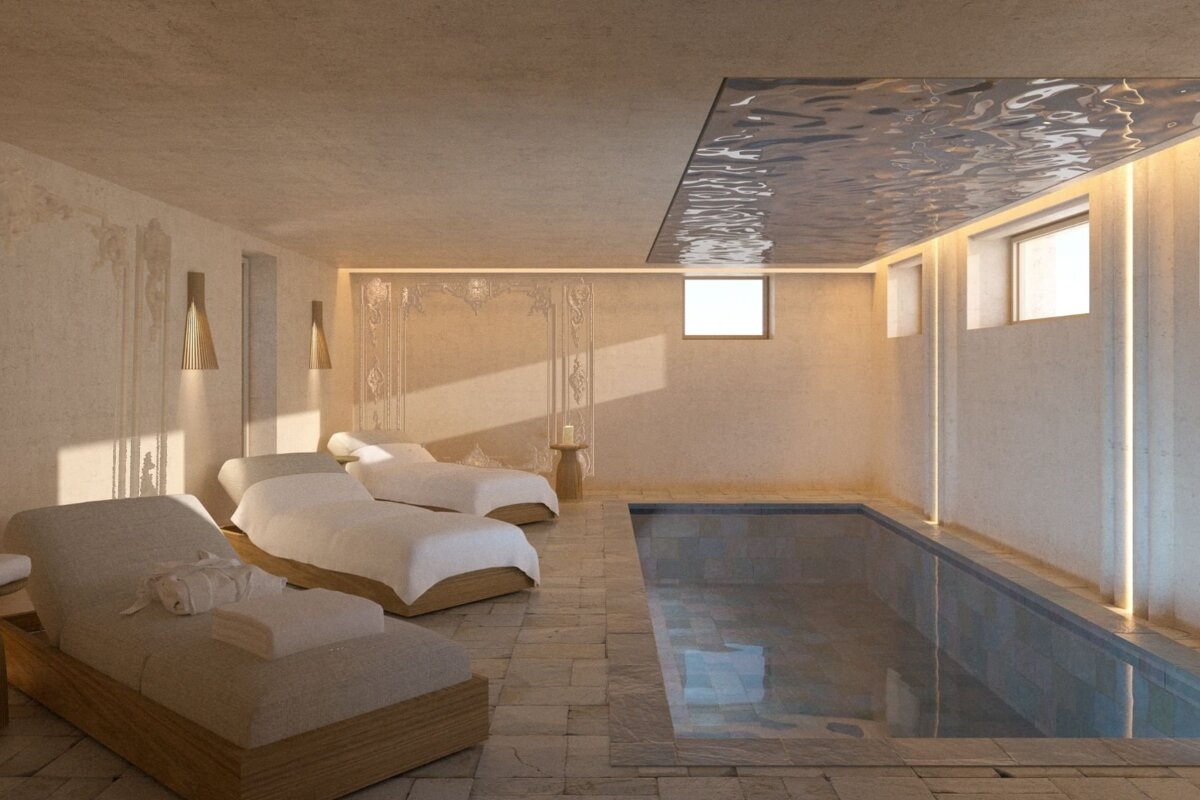 A minimalist spa room features serene lounge beds, an indoor pool, and a unique rippled reflective ceiling, bathed in warm, soft light.