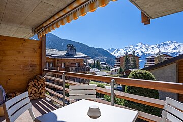 A balcony with mountains in the background and a table and chairs