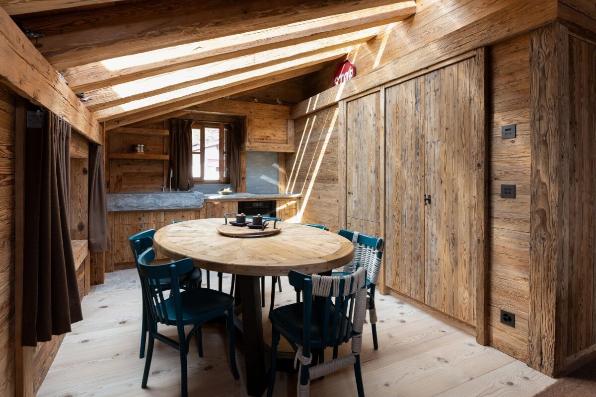 A wooden room with a round table and blue chairs