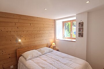 A bedroom with a wooden wall and a bed